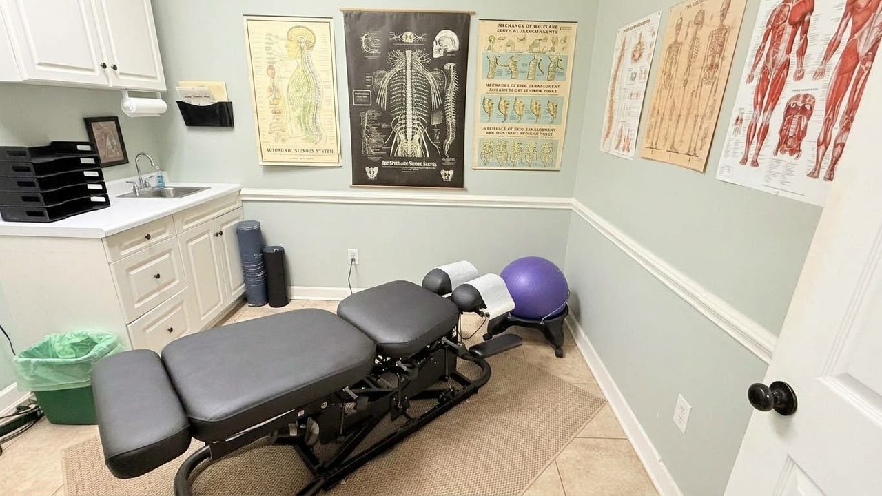 Adjustment room with a chiropractic table, spine and muscle charts and an exercise ball