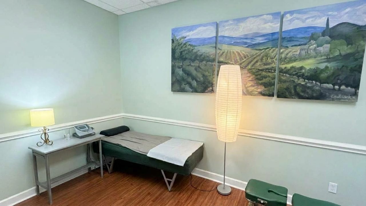 Treatment room with a landscape painting, a soft floor lamp and a green treatment table