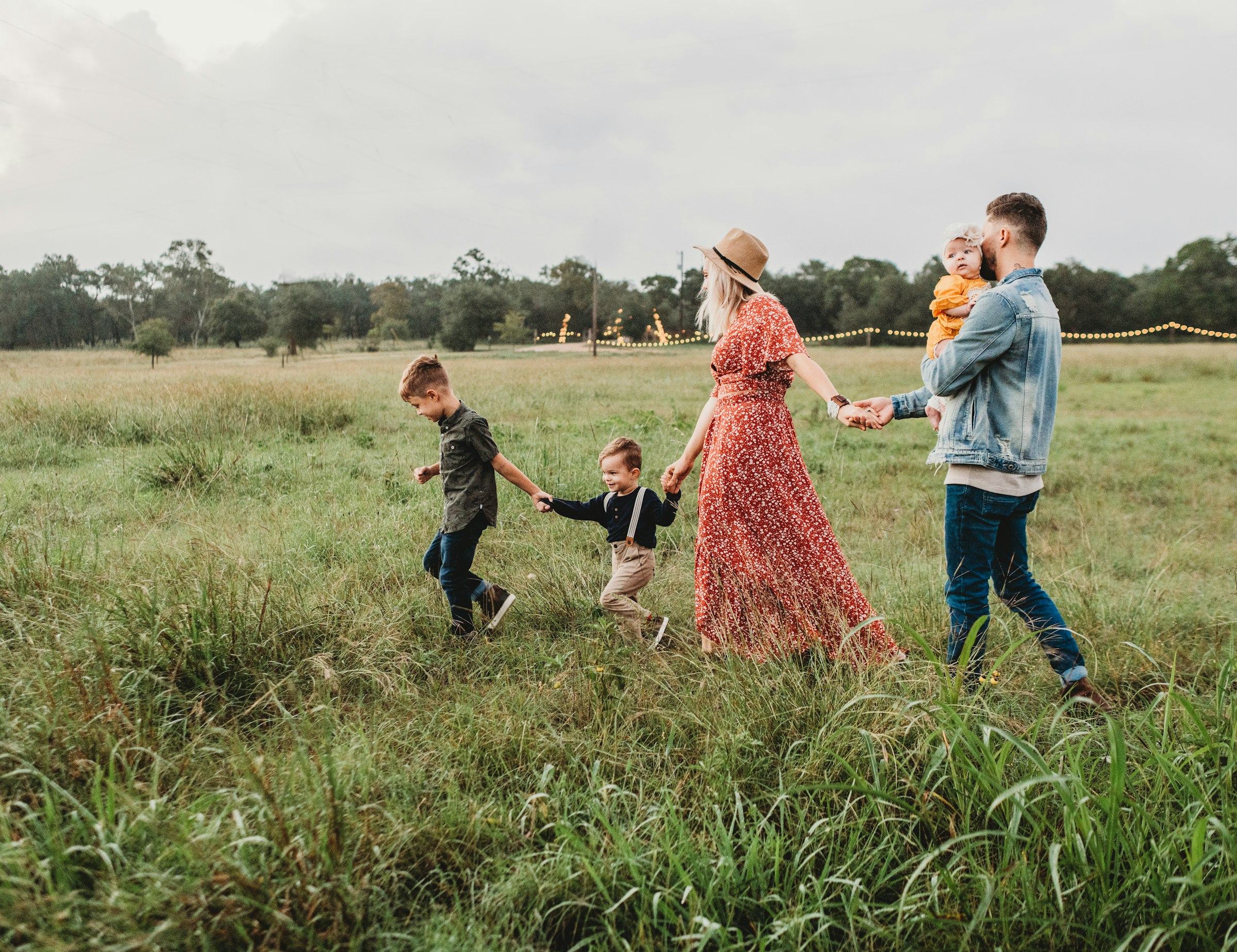 A family holding hands as they walk through a grassy field