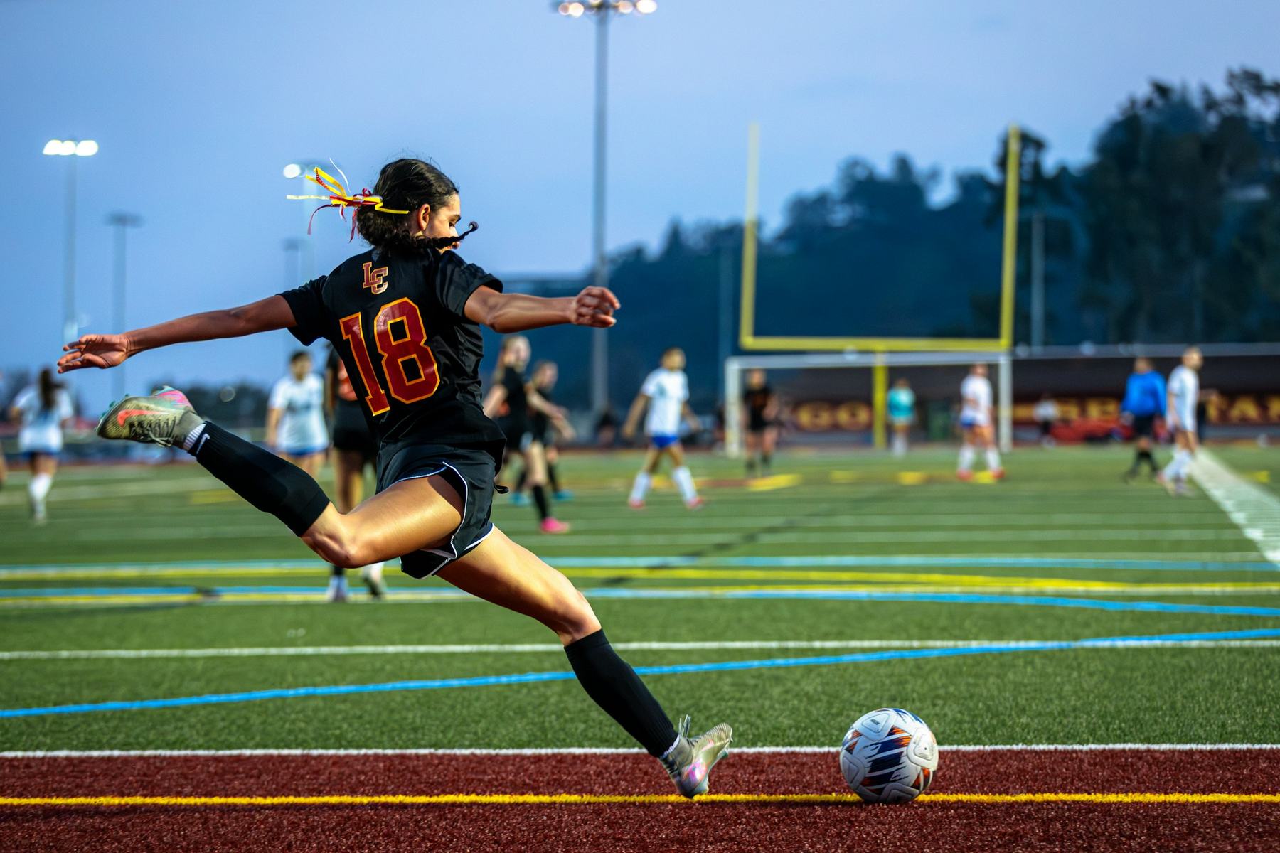 A high school soccer player in mid-kick during a game
